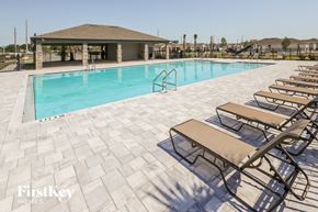 Kissimmee house for rent - A pool with sun loungers and a pavilion in the background.