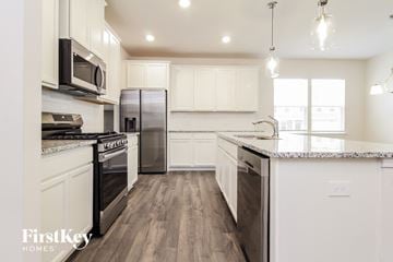 Greer house for rent - a kitchen with white cabinets and stainless steel appliances