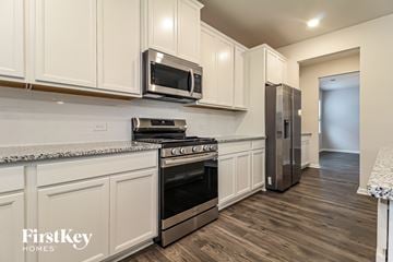 Greer house for rent - A kitchen with white cabinets and a stainless steel refrigerator.