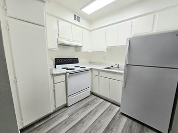 Wildomar multi-family for rent - A kitchen with white cabinets and a grey fridge.