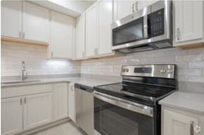 Holland apartment for rent - a kitchen with white cabinets and a stove and a microwave