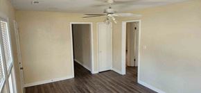 Clinton house for rent - A room with a ceiling fan and wooden floors.