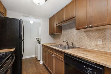 Nashville apartment for rent - A kitchen with a black refrigerator and wooden cabinets.