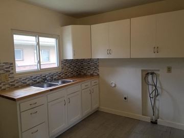 Youngstown house for rent - a kitchen with white cabinets and a sink and a window