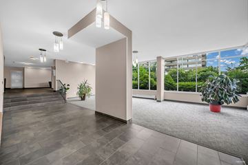 New Westminster apartment for rent - A spacious room with a grey floor and a large window overlooking a green area.