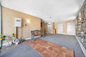 White Rock apartment for rent - A room with a bench, a vase with flowers, and a brick wall.