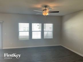 Charlotte house for rent - an empty living room with a ceiling fan and three windows