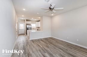Lewisville house for rent - an empty living room with a ceiling fan and a kitchen