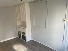 Chester apartment for rent - A white cabinet with a drawer and a shelf is in the corner of a room with a wooden floor.