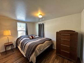 Sitka house for rent - A bedroom with a bed, nightstand, and window.
