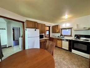 Sitka house for rent - A kitchen with a white refrigerator, wooden cabinets, and a wooden table.