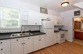 Cincinnati house for rent - a kitchen with white cabinets and a sink and a refrigerator
