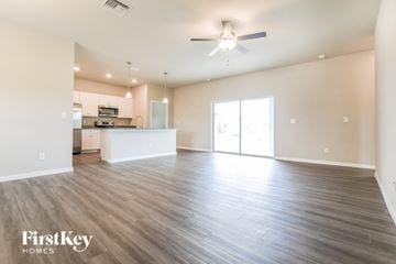Port Charlotte house for rent - A spacious living room with a kitchen in the background and a ceiling fan above.