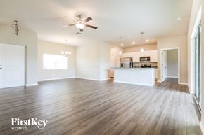 Port Charlotte house for rent - A spacious living room with a kitchen in the background and a ceiling fan above.