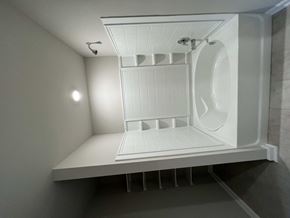 Youngsville house for rent - A white shower stall with a bench and a shower head.