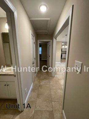 Wilson apartment for rent - A hallway with tile flooring and white walls, with a sign that reads "W. Hunter Company Inc." and "Unit 1A".