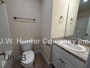 Wilson apartment for rent - A bathroom with a toilet, sink, and mirror.