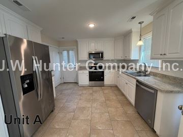 Wilson apartment for rent - A kitchen with a stainless steel refrigerator and white cabinets.