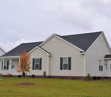 Goldsboro apartment for rent - A house with a grey roof and white siding with green shutters.