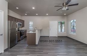 Durant apartment for rent - A well-lit, empty kitchen and living room with a wood floor and a ceiling fan.