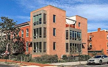 Washington apartment for rent - A red brick building with a white car parked in front.
