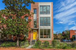 Washington apartment for rent - A modern house with a yellow door is surrounded by greenery.