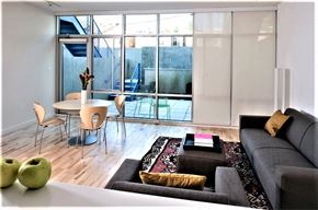 Washington apartment for rent - A living room with a grey couch, a white table, and a glass door leading to a balcony.