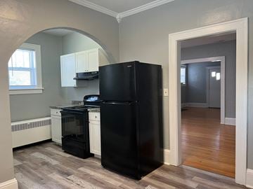 Roanoke apartment for rent - A black fridge and dishwasher in a kitchen with wooden floors.