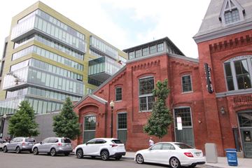 Washington apartment for rent - A white car is parked in front of a red brick building.