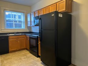 Roanoke apartment for rent - A black refrigerator in a kitchen with wooden cabinets.