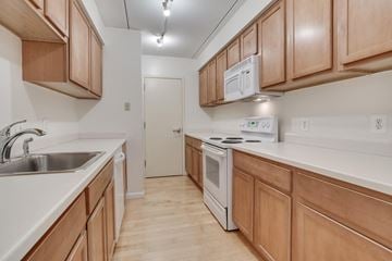 Washington apartment for rent - A kitchen with wooden cabinets and a white stove top oven.