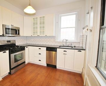 Washington apartment for rent - A kitchen with white cabinets and a black stove top oven.