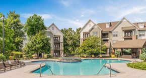 Chattanooga apartment for rent - A large swimming pool in front of a two-story house with a deck and lounge chairs.