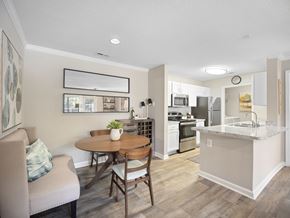 Newnan apartment for rent - A modern kitchen with a dining table and chairs in the foreground and a kitchen island in the background.