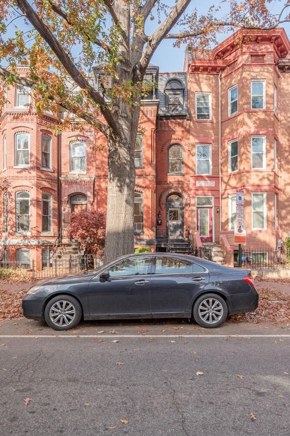 Washington apartment for rent - A black car is parked in front of a red brick building.