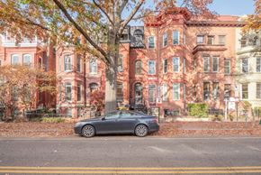 Washington apartment for rent - A car is parked on the side of a street in front of a row of houses.