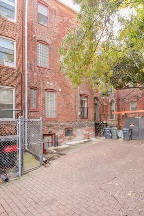 Washington apartment for rent - A red brick building with a fence and trees in front.