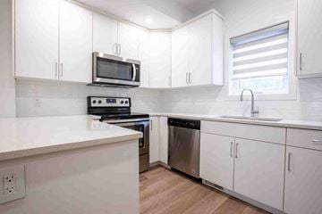 Winnipeg apartment for rent - A kitchen with white cabinets and a black microwave.