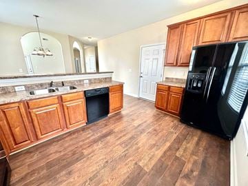 Greer house for rent - A kitchen with wooden cabinets and a black refrigerator.