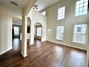 Greer house for rent - A spacious room with wooden floors and arched columns.