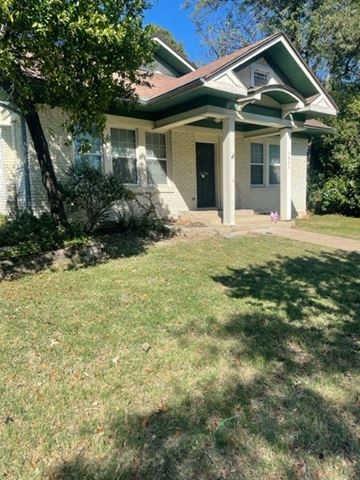 Dallas apartment for rent - A house with a green roof and white walls with a black door and windows.