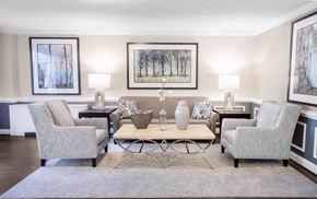 Towson apartment for rent - A living room with a grey sofa, two chairs, a coffee table, and two wall lamps.