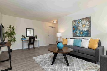 Towson apartment for rent - A living room with a grey couch, a wooden coffee table, and a painting on the wall.
