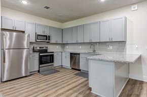 Spring apartment for rent - a kitchen with white cabinets and stainless steel appliances