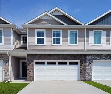 Waukee apartment for rent - A modern house with a stone wall and two white garage doors.