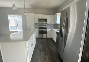 Urbandale apartment for rent - A modern kitchen with white cabinets and a stainless steel refrigerator.