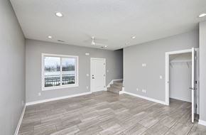 Waukee apartment for rent - A spacious room with a large window, hardwood flooring, and a ceiling fan.