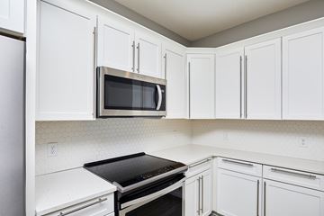 Waukee apartment for rent - A kitchen with white cabinets and a black stove top oven.