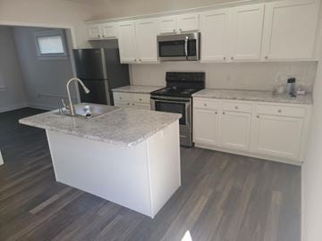 Lima apartment for rent - A kitchen with a granite island and white cabinets.