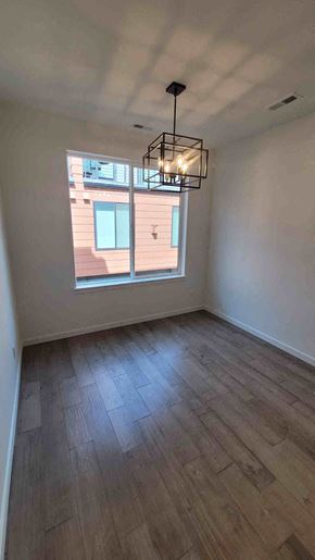 Denver apartment for rent - A room with wooden flooring and a window showing a building outside.